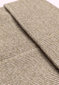 Textielstof in lichtbeige, met een geweven textuur en een subtiel patroon; twee gevouwen lagen die de structuur en dikte van de stof tonen.