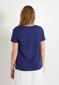 Camiseta de algodón azul marino de manga corta, con cuello redondo y corte recto, mostrada desde la parte posterior. Textura suave, diseño minimalista.