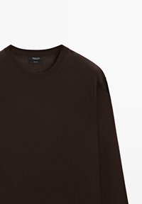 Pull en laine marron avec un col rond, des manches longues et une texture lisse. L'étiquette au niveau du col indique que le matériau est 100 % laine.
