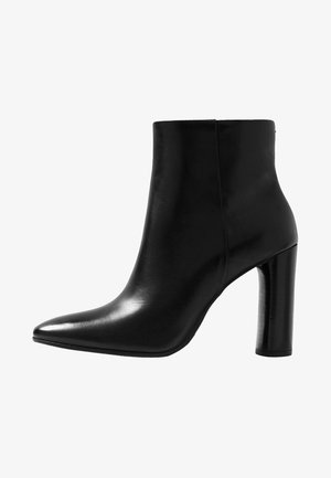 Černá kožená kotníková bota s špičatou špičkou a vysokým válcovým podpatkem. Hladký povrch s elegantní siluetou a bez viditelného kování.