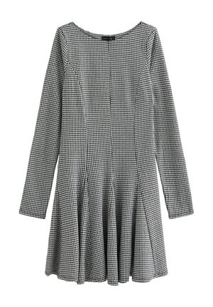 Zwart-witte geblokte jurk met lange mouwen, iets uitlopende rok, gladde stof en een ronde halslijn. Heeft verticale naden.