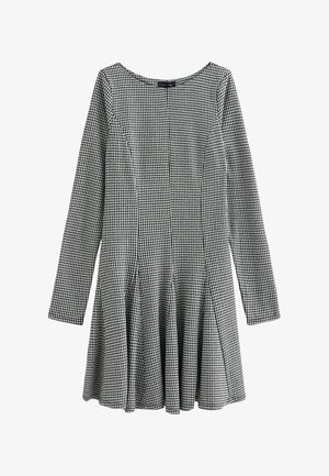 Robe à carreaux noir et blanc avec des manches longues, jupe légèrement évasée, tissu lisse et encolure ronde. Présente des coutures verticales.