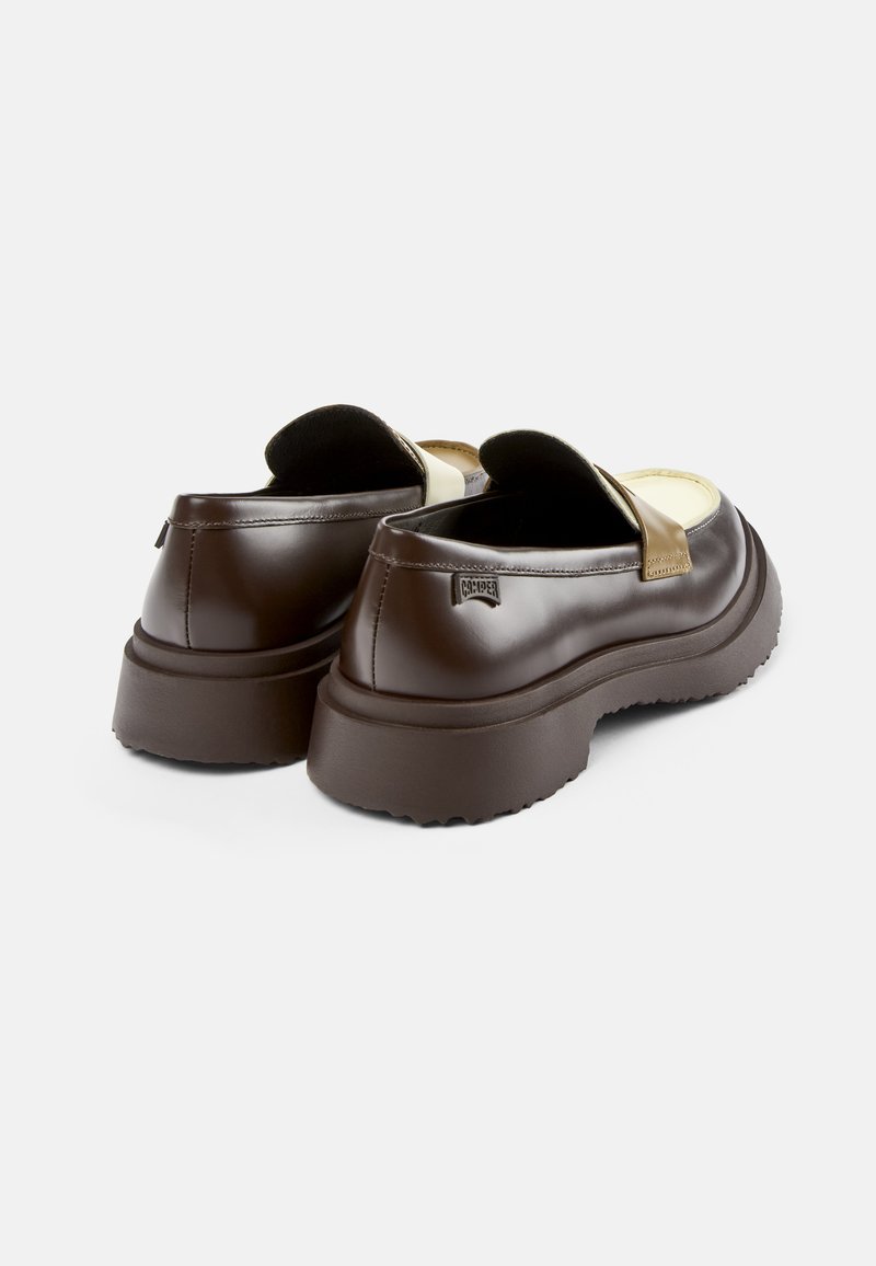 Chaussures brunes à enfiler avec une finition en cuir lisse, une sangle accentuée en or, une semelle en caoutchouc épaisse et un design de bout arrondi.