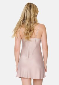 Abito sottile in satin di un delicato rosa, caratterizzato da spalline sottili e un orlo svasato. Texture liscia con un design minimalista.