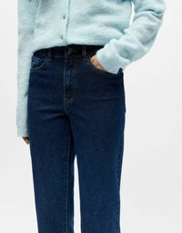 Svijetloplavi, teksturirani kardigan s gumbima upareni s tamnoplavim trapericama visokog struka koje imaju prednje džepove i kontrastno šivanje.