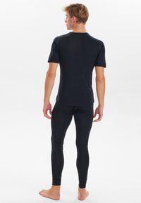 Sort tætsiddende kortærmet skjorte og matchende leggins, lavet af letvægtigt materiale, med en glat overflade og ingen synlige mønstre.