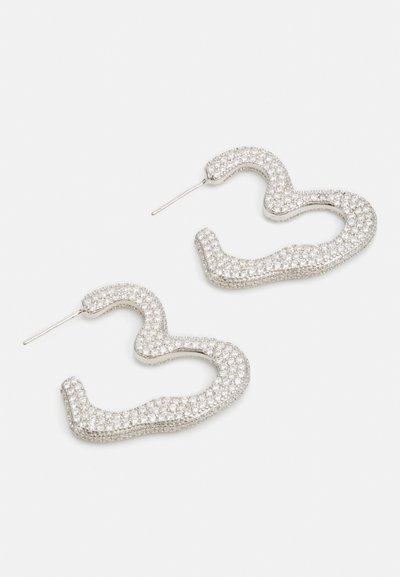 Silver-tone earrings featuring a wavy, snake-like design, encrusted with sparkling clear crystals. Includes a straight post for fastening.