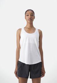 Fehér, ujjatlan sportos tank top kerek nyakkal; fekete sportos rövidnadrággal párosítva, amely oldalvarrással és struktúrált anyaggal rendelkezik.