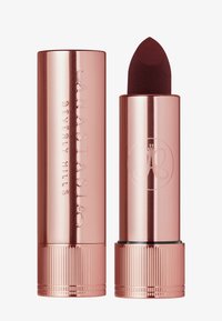 Roze-gouden lippenstiftbuis met een afgeronde bovenkant, gegraveerd logo en een gestructureerde basis. De lippenstift heeft een diepe bordeauxrode tint.