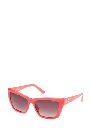 Lunettes de soleil en plastique rose avec une forme géométrique en œil de chat, verres teintés en dégradé et accent logo doré sur la branche.