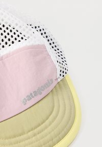 Άσπρο δίχτυ και ροζ υφασμάτινο καπέλο μπέιζμπολ με ανοιχτό κίτρινο κυρτό γείσο και γκρι λογότυπο "patagonia" στην ροζ περιοχή.