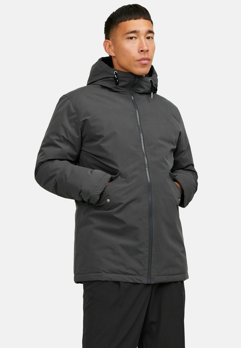 Dark gray insulated jacket with a hood, front zip closure, and side pockets; features a smooth texture and adjustable drawstrings.