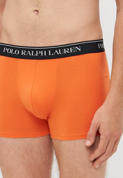 Oranžinės medvilninės boxer kelnaitės su juodu elastiniu juosmeniu, ant kurio baltomis raidėmis yra užrašyta "POLO RALPH LAUREN". Prigludusi dizaino forma su lygiu paviršiumi.