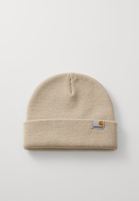 Beige knit beanie with a folded cuff, featuring a small square brand tag with a logo. Soft texture and flexible fit.