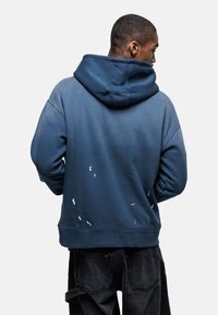 Felpa blu con cappuccio, caratterizzata da un design a gradiente, dettagli usurati e una vestibilità comoda. Realizzata in tessuto morbido.