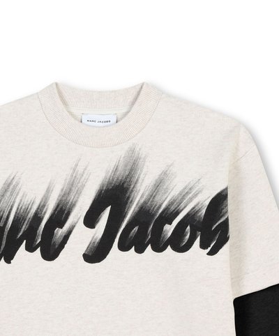 Felpa beige chiaro con un audace design a pennellate nere che presenta la scritta "Marc Jacobs" sulla parte frontale. Collo a coste, maniche lunghe.