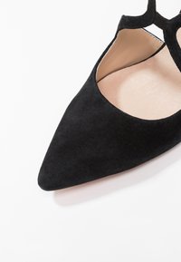 Ballerine nere in suede con punta, caratterizzate da un design con ritagli, un interno liscio e una forma minimalista. Adatte per varie occasioni.