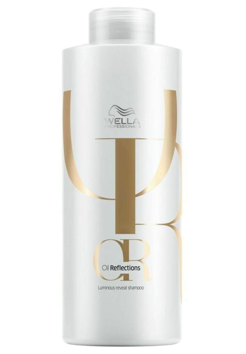 Witte shampoofles met een glanzende afwerking, grote gouden letters en een schroefdop. De tekst bevat "Oil Reflections" en "Luminous reveal shampoo."