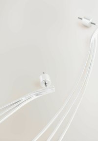 Stik med metalrundt ender forbundet til skinnende sølvkabler, med en glat tekstur og strømlinet design mod en lys baggrund.