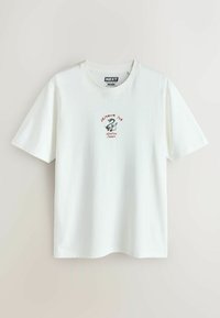 Fehér pamut póló, kis grafikával és az "Okinawa Ink" felirattal, sárkány motívummal, kerek nyakkivágással és rövid ujjakkal.