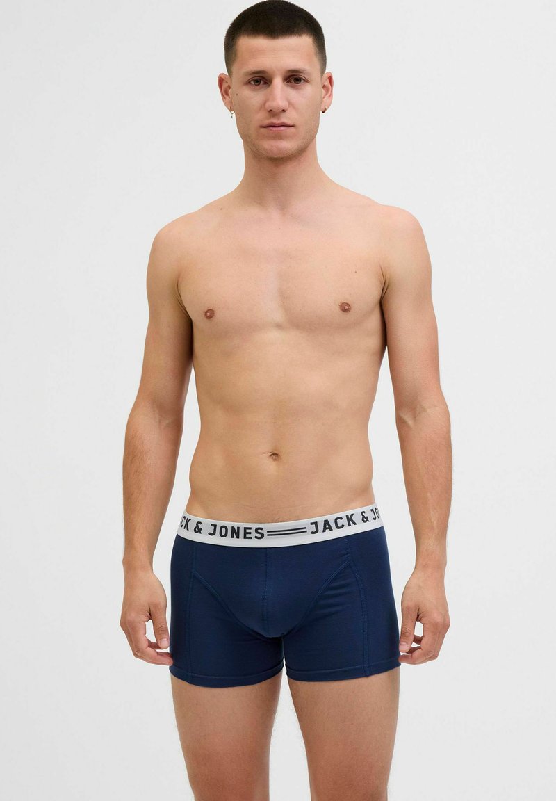 Tumši zili bokseršorti, kas izgatavoti no elastīga auduma, ar elastīgu jostasvietu, kurā ir balts un melns "JACK & JONES" logo.