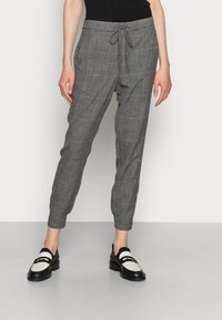 Grijze geruite tapershorts met een trekkoord in de taille, voorzien van een gladde textuur en zijzakken, gecombineerd met zwart-witte instappers.