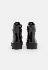 Mustad mustan nahast ankle-botted, millel on sile pind, madal konts ja külgzipp mugavaks selga panemiseks. Logo on nähtav kontsul.