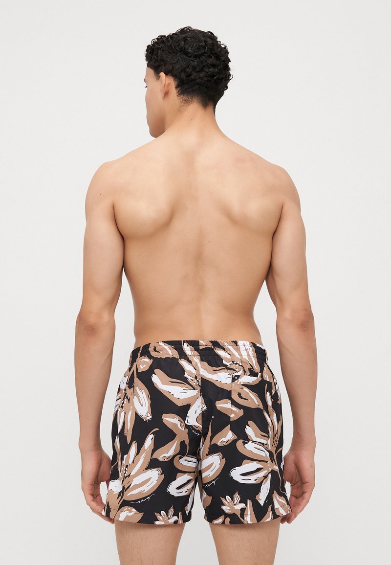 Męskie szorty kąpielowe w kolorze czarnym, z beżowym i białym wzorem kwiatowym. Elastyczny pasek w talii z sznurkiem do regulacji, długość powyżej kolana.