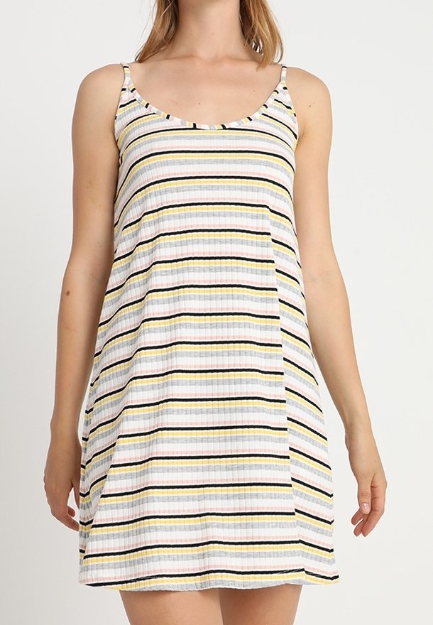 Mujer vistiendo un vestido sin mangas, de longitud hasta la rodilla, con rayas horizontales en blanco, negro, amarillo y rosa sobre un fondo claro.