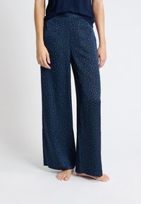 Navy wijde broek met een groen abstract patroon. Gemaakt van soepele stof, met een elastische tailleband en een relaxte pasvorm door het geheel.
