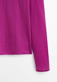 Pull en tricot magenta à manches longues, montrant le bas du torse et le bras droit sur un fond blanc.