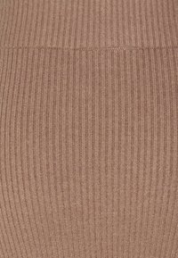 Tissu côtelé dans une teinte rose douce, présentant de fines lignes verticales avec une texture douce et extensible, adapté aux vêtements ajustés.