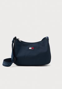 Geantă de umăr Tommy Jeans de culoare albastru marin, cu curea ajustabilă și închidere cu fermoar, având patch-ul cu logo-ul brandului pe partea din față.