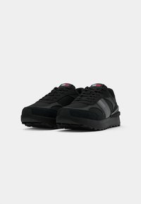 Black athletic shoes featuring a mix of mesh and synthetic materials, a textured upper, and gray accent stripes on the sides.