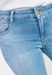 Lichtblauwe denim jeans met een slim fit ontwerp, voorzien van een gouden knoop, contrasterende stiksels en een klassieke vijf-pocketstijl.