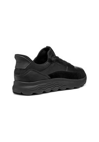 Svarta sneakers i läder och mocka, med en dämpad sula, texturerad design och en logotyp på hälen.