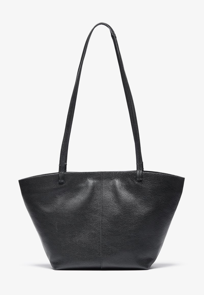 Sac cabas en cuir noir texturé avec de longues poignées et une forme légèrement trapézoïdale, présenté sur un fond clair uni.