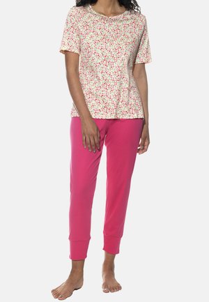 Blusenshirt mit kurzen Ärmeln in Weiß mit rosa und grünen Mustern, kombiniert mit einfarbigen, rosafarbenen, knöchellangen Hosen mit umgeschlagenen Säumen.