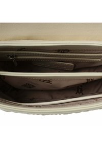 Interno di una borsa in beige chiaro con compartimenti organizzati, una tasca con zip e una fodera in tessuto brandizzato con una texture liscia.