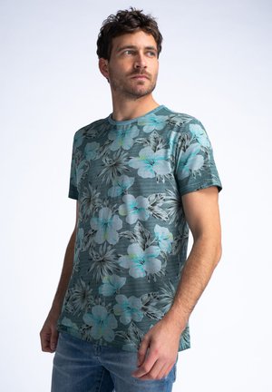 Camisa de manga corta en teal con un estampado floral que presenta grandes flores en azul claro y gris, escote redondo y una tela suave y texturada.