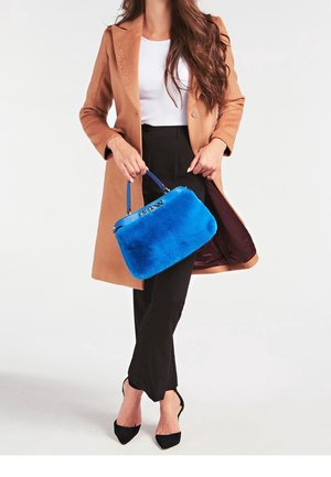Niebieska torebka z futerka sztucznego o ustrukturyzowanym kształcie, z uchwytami na górze i błyszczącym, niebieskim zamkiem błyskawicznym. Noszona z beżowym płaszczem i czarnymi spodniami.