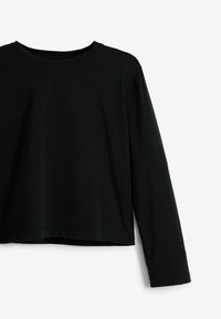 Top nero a maniche lunghe realizzato in morbido cotone, con scollatura rotonda e un design cropped caratterizzato da una texture liscia. Cuciture pulite e minimaliste.