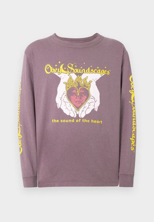 Dugi rukav purpurni majica od pamuka s grafikom ruku koje drže srce s plamenovima i tekstom u žutoj boji na prednjoj strani i rukavu.