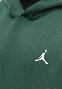 Fleece verde feito de tecido macio com capuz ajustável. Apresenta um logo Jumpman branco em destaque na área do peito.