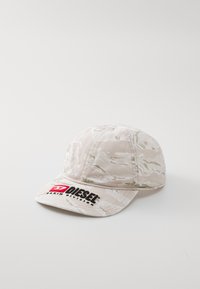 Sapca de baseball de culoare bej deschis cu un model de camuflaj, având un logo Diesel negru și roșu pe față. Textura materialului este netedă.