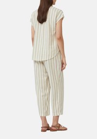Ensemble en lin composé d'un haut à manches courtes et d'un pantalon ample et court, dans un motif rayé crème et beige. Sandales marron.