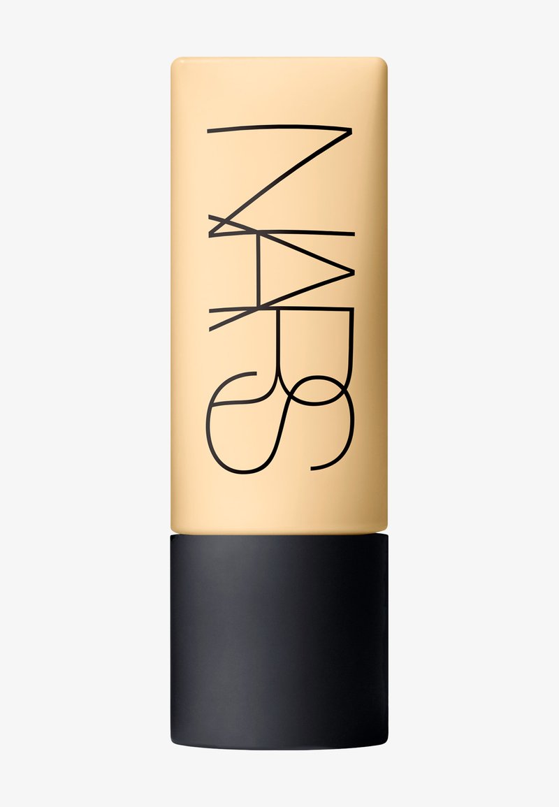 Fond de teint NARS dans un flacon rectangulaire transparent avec un corps beige et un capuchon noir, arborant un texte logo noir en gras verticalement sur le côté.