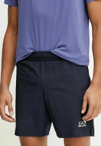 Pantaloni sportivi blu navy con cintura elastica e un piccolo logo sul lato sinistro. Realizzati in materiale leggero e liscio.