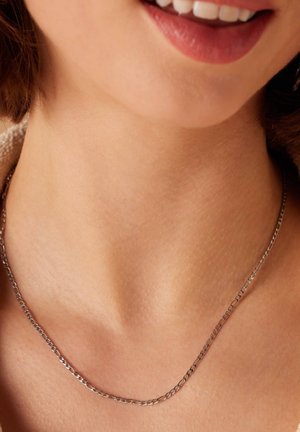 Zilveren ketting met een verfijnd schakelontwerp, rustend op een gladde hals. Subtiele glans op het metaal, minimalistische esthetiek.