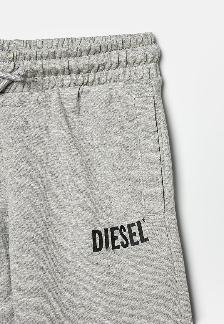 Pantalones de chándal grises hechos de una suave tela texturizada, con una cintura elástica, bolsillo lateral y el logo negro "DIESEL" cerca del dobladillo.